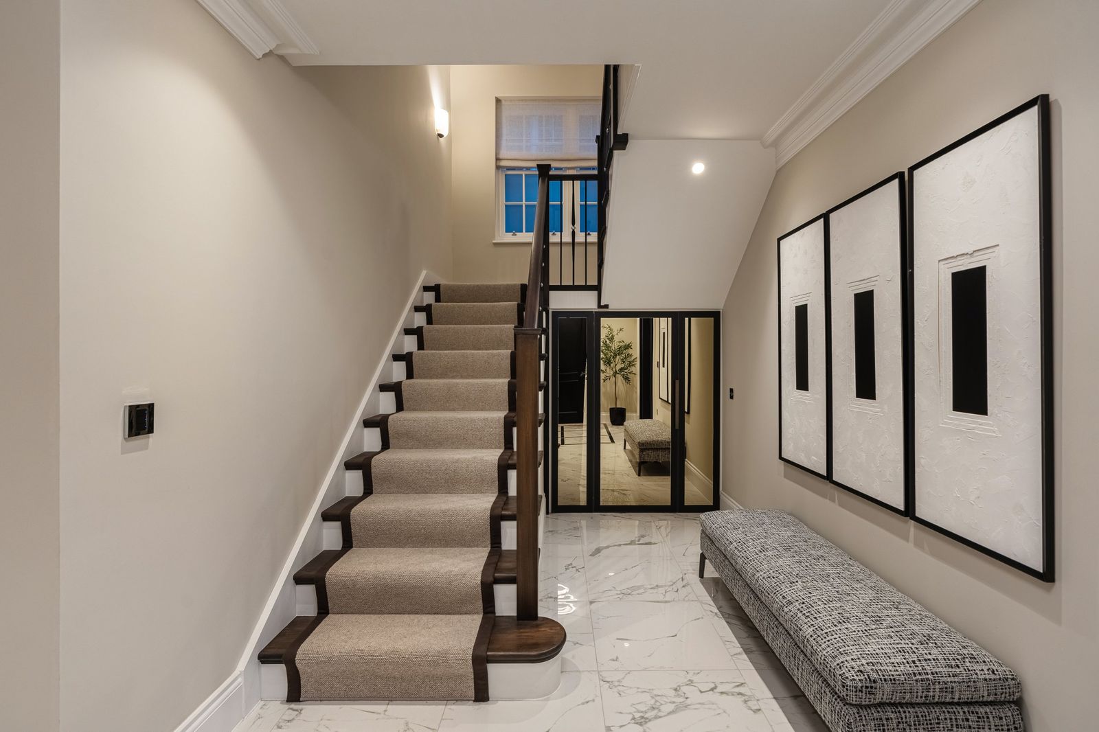 The entrance hall with a marble floor and runner stairs