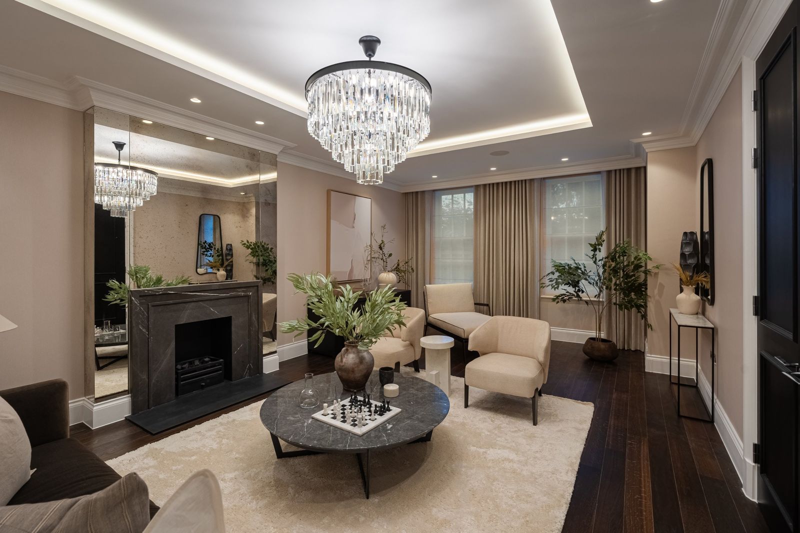 The sitting room with a crystal chandelier and marble fireplace