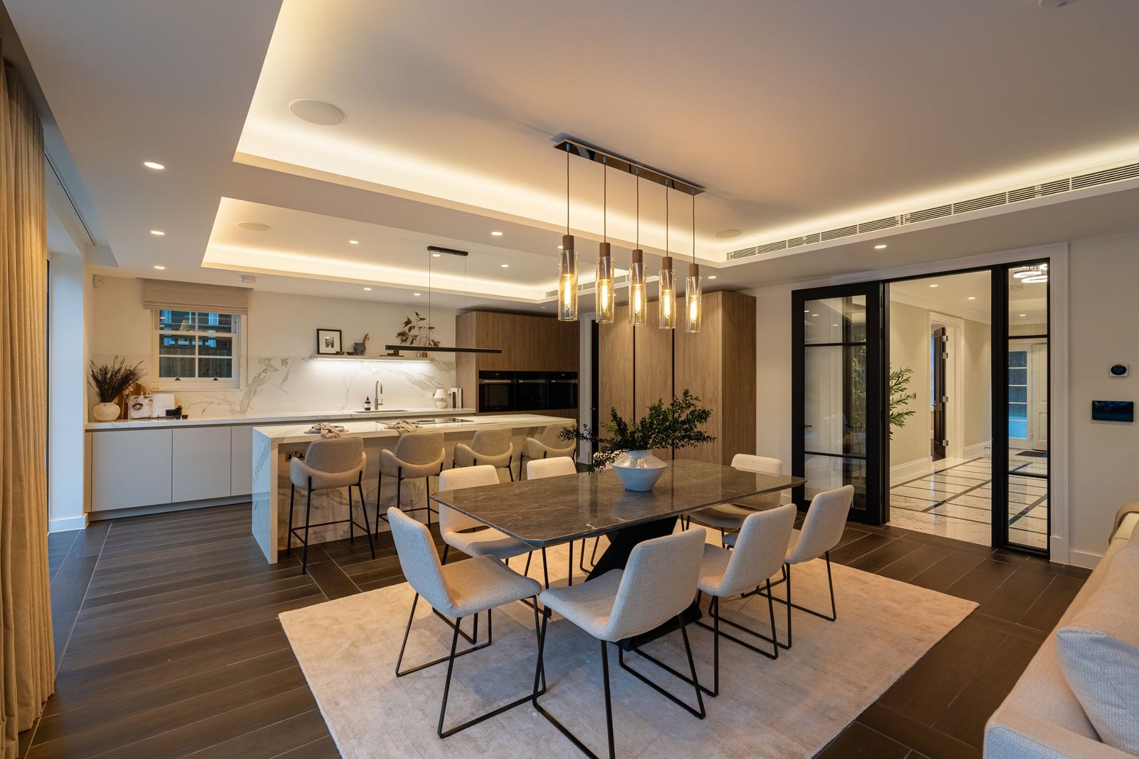 The dining area and kitchen under warm pendant lights
