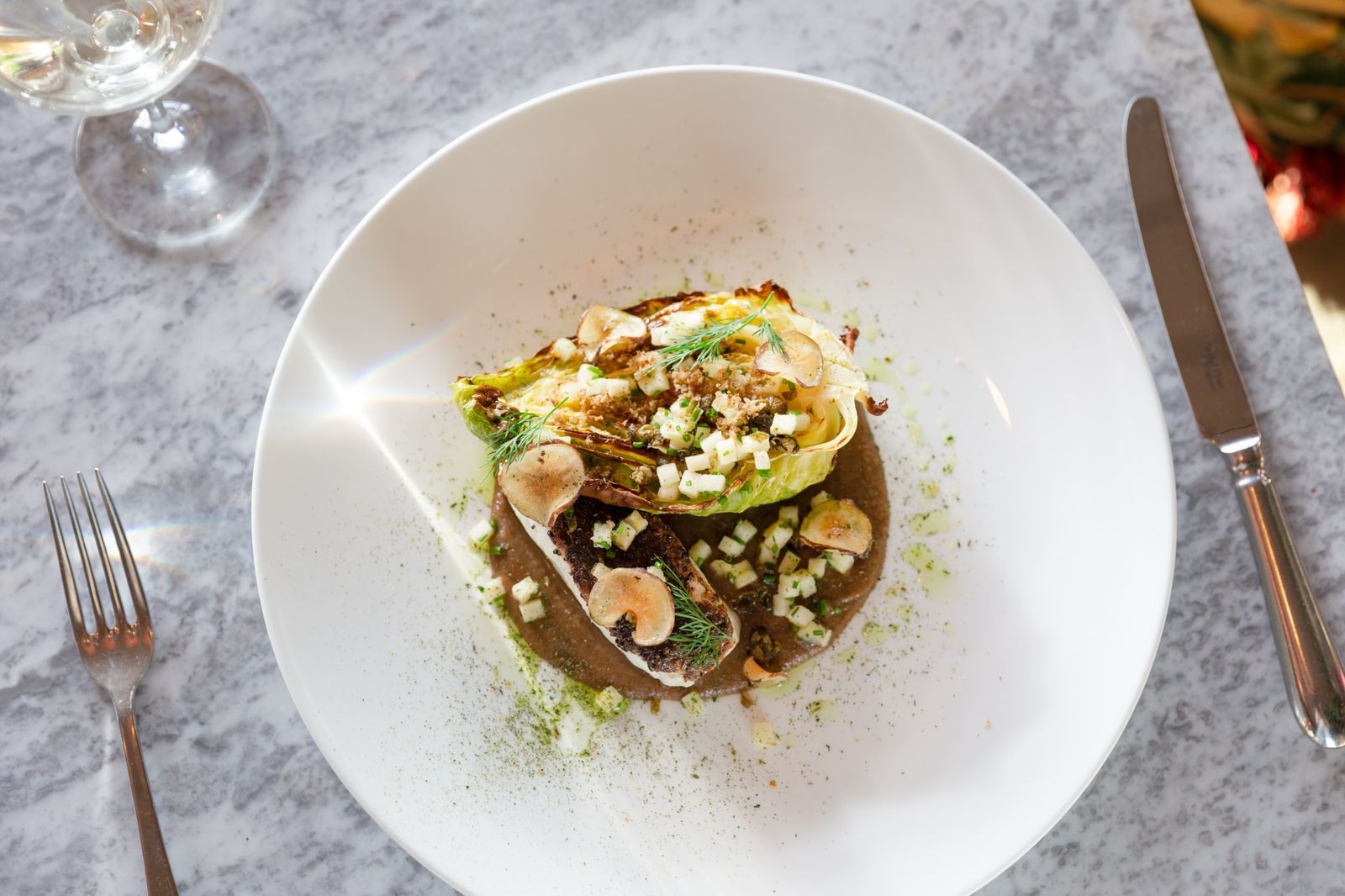 Roasted hispi cabbage and fish on a white plate, from above