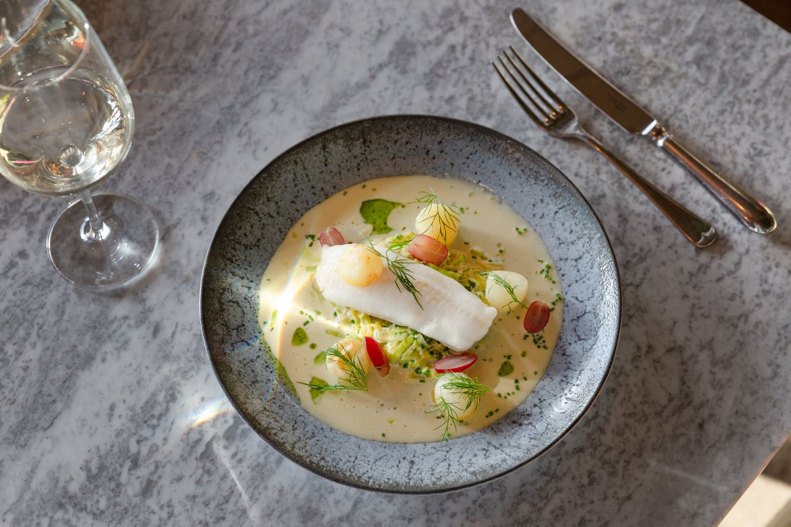 Poached white fish with leeks, grapes and a butter sauce, from above