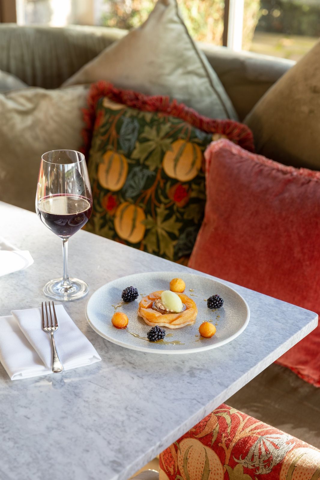 A fruit tart with blackberries and sorbet beside a glass of red wine