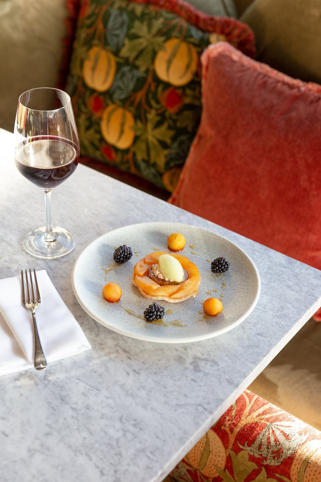 A fruit tart with blackberries and sorbet against patterned cushions