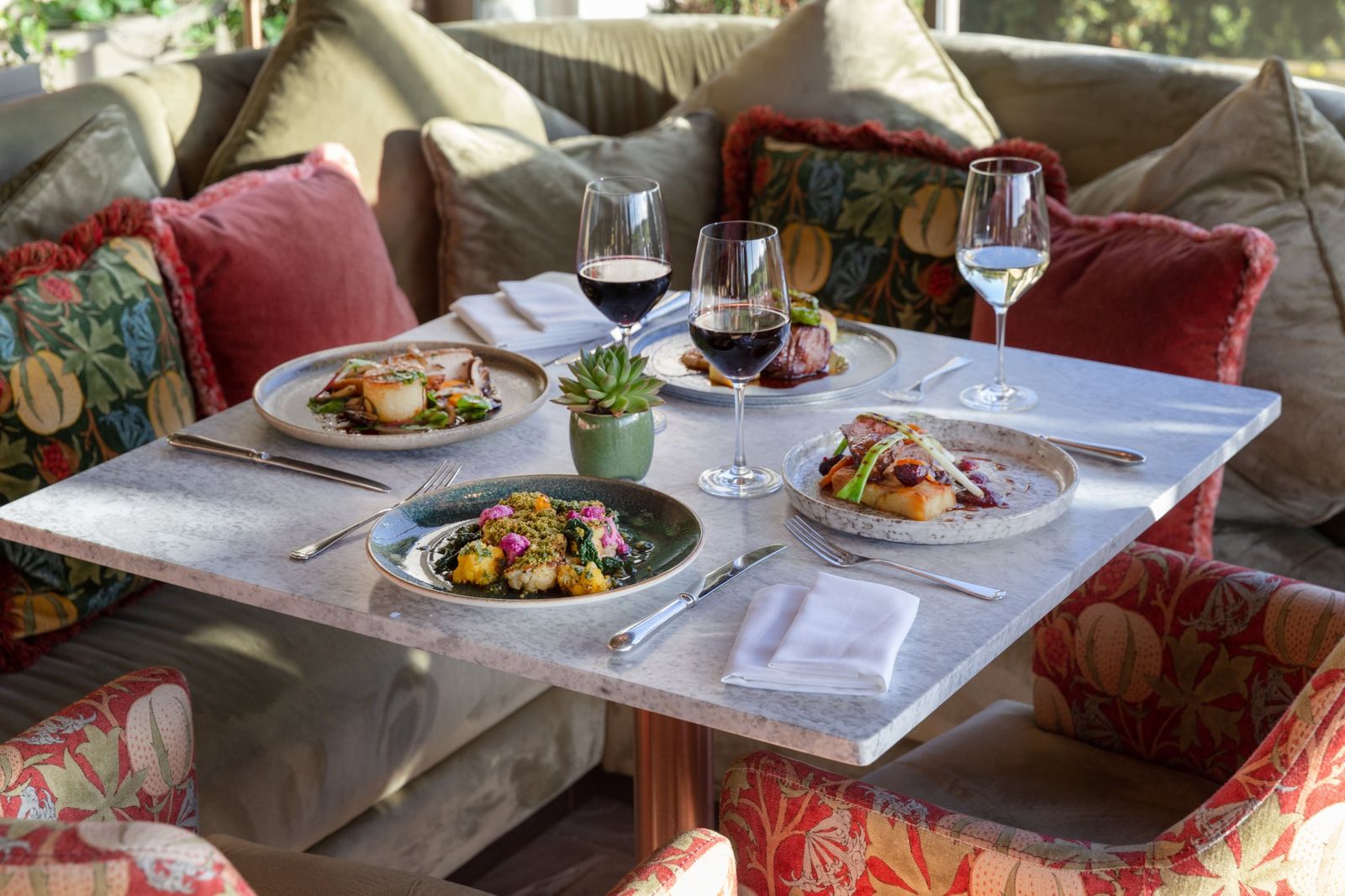 A table of winter dishes with red and white wine against the velvet banquette