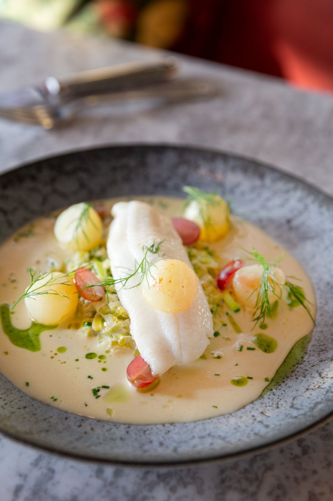 Poached white fish with leeks, grapes and a butter sauce