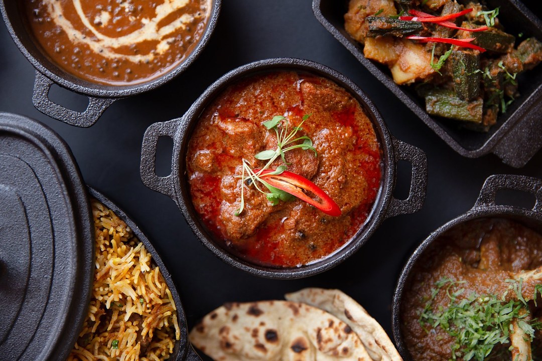 Indian curries in cast-iron pots with rice and naan