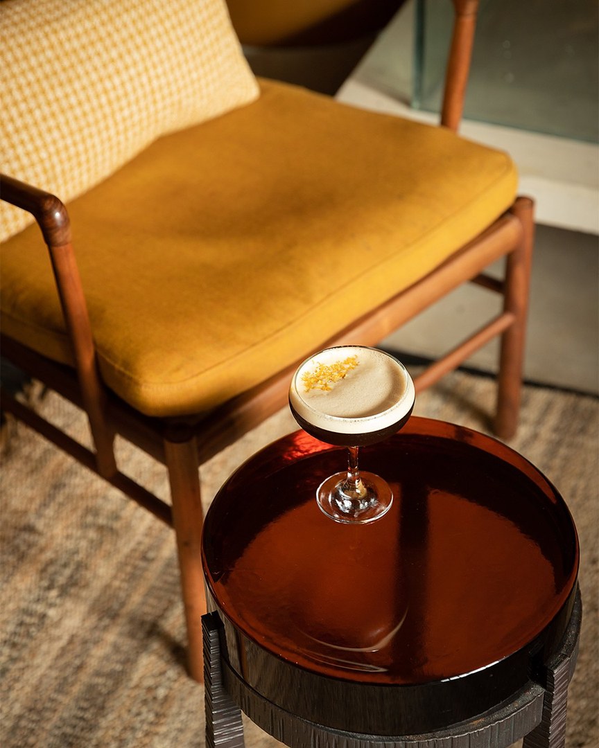 An espresso martini beside a mustard armchair