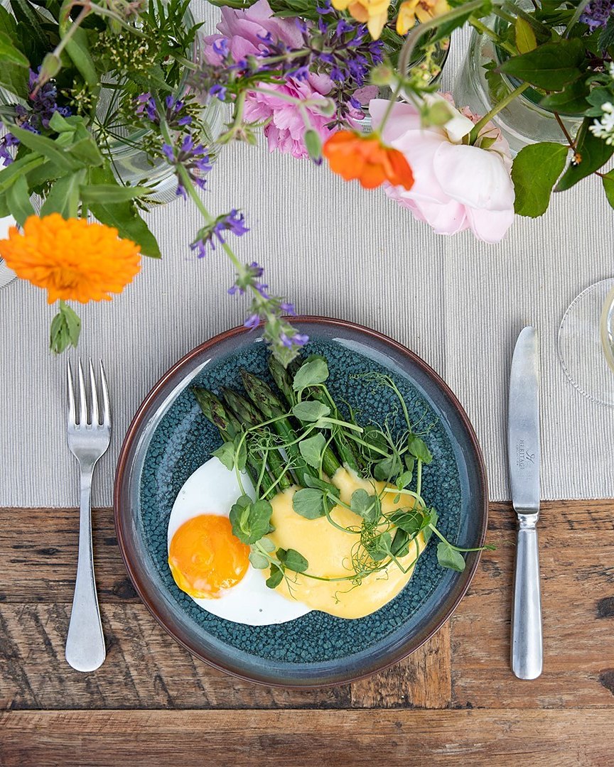 Asparagus with hollandaise and a fried egg among garden flowers