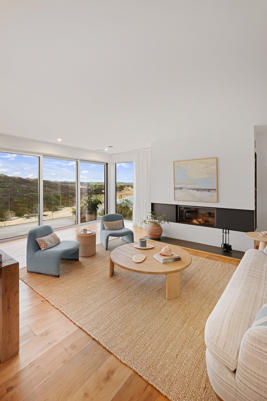 A coastal living room styled with a coffee table book, shell and plants