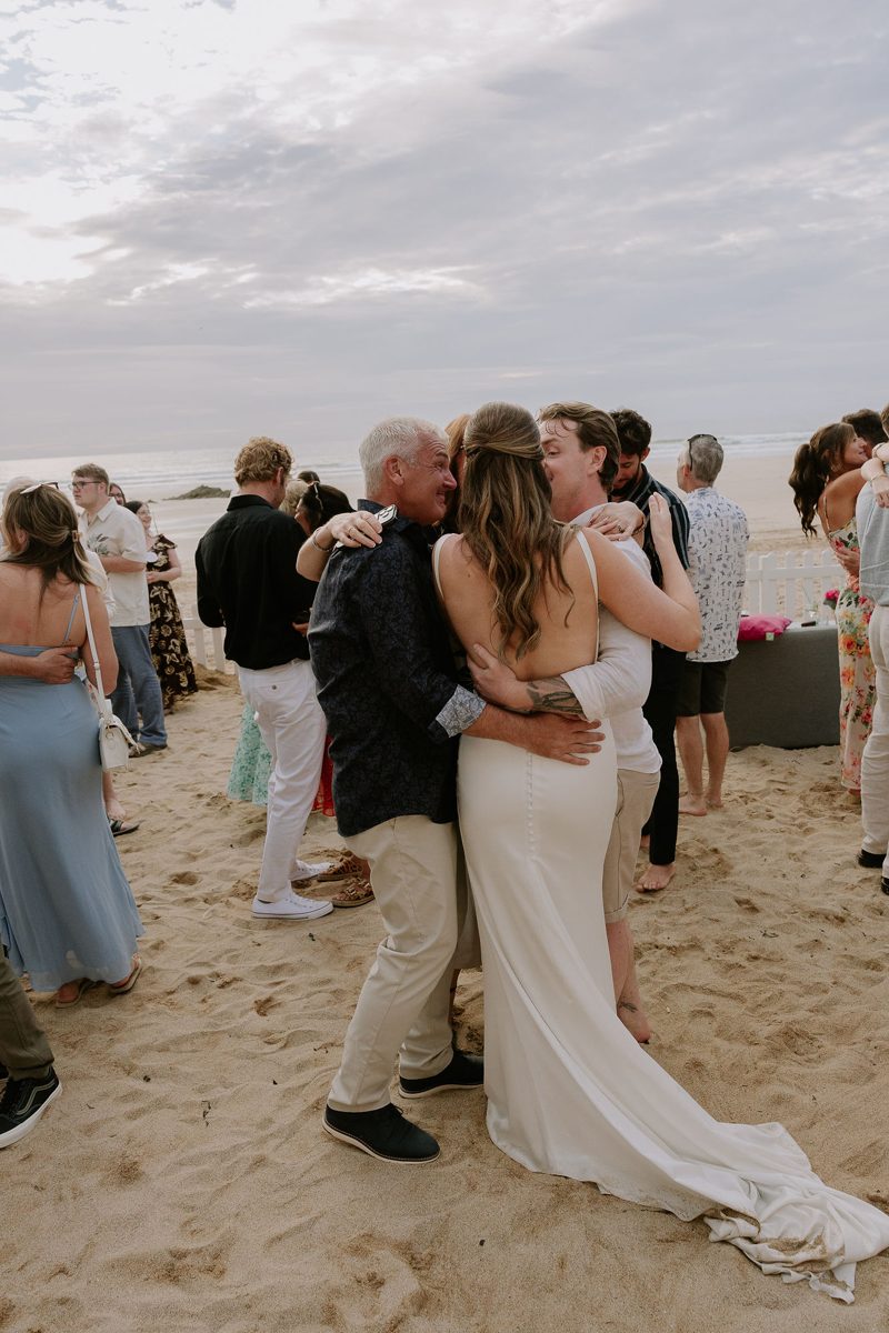 Family hugging on the beach at Kelly and Martin's wedding