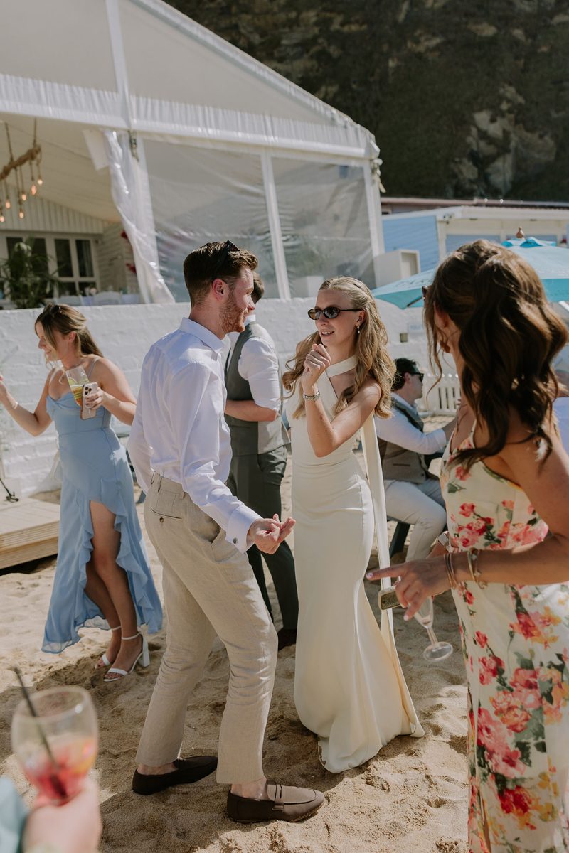Friends dancing on the beach in the sunshine