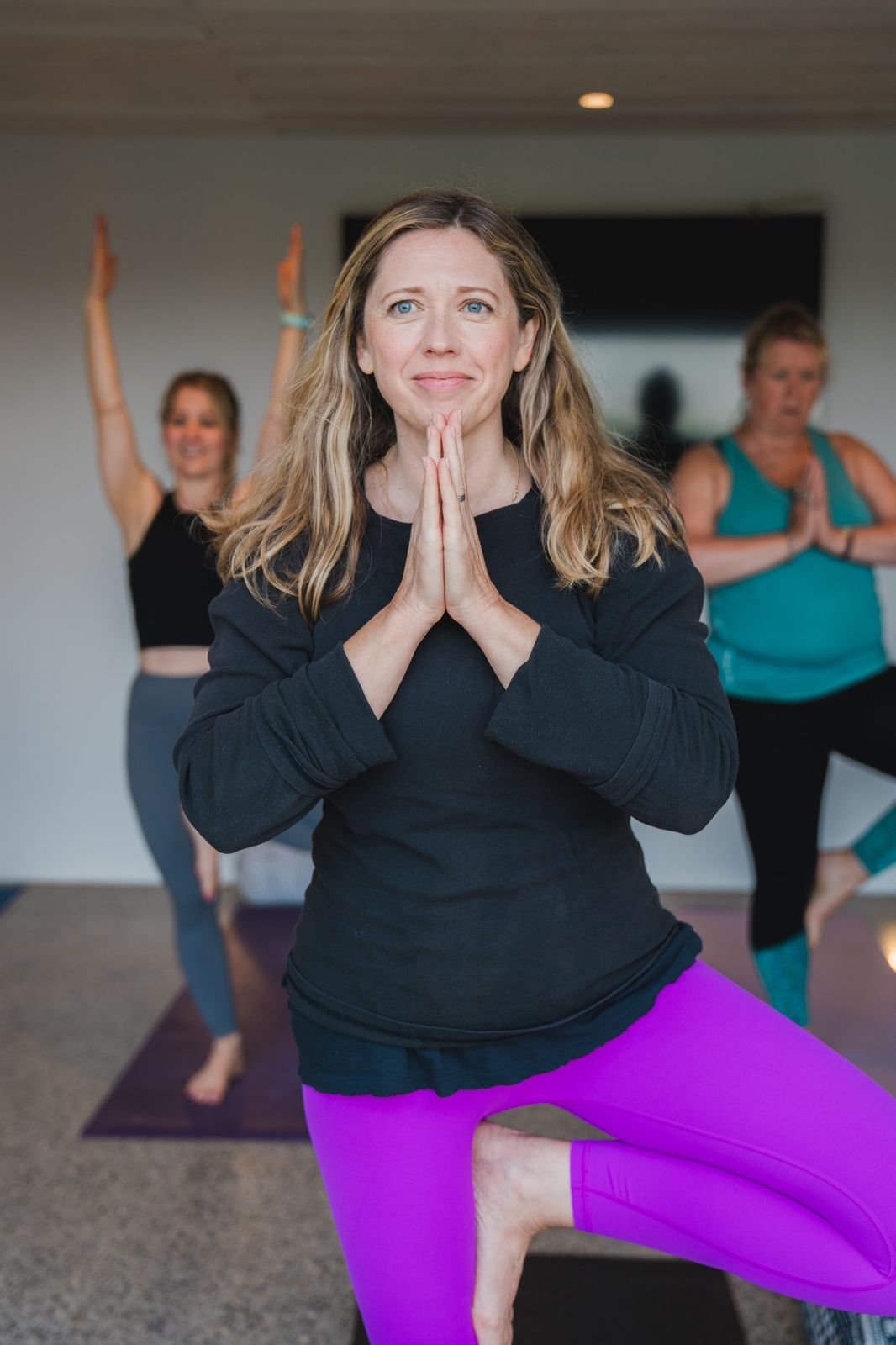 A Yoga Flow guest in tree pose with the class behind her