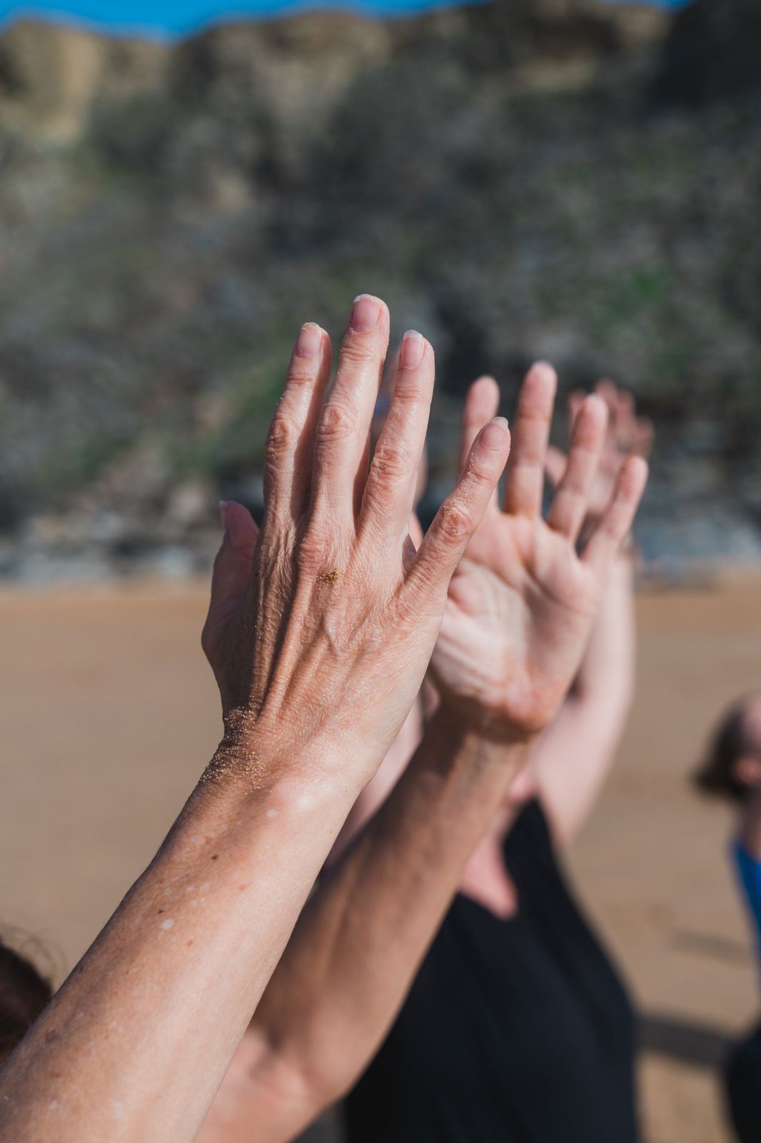 Sandy hands raised on the beach