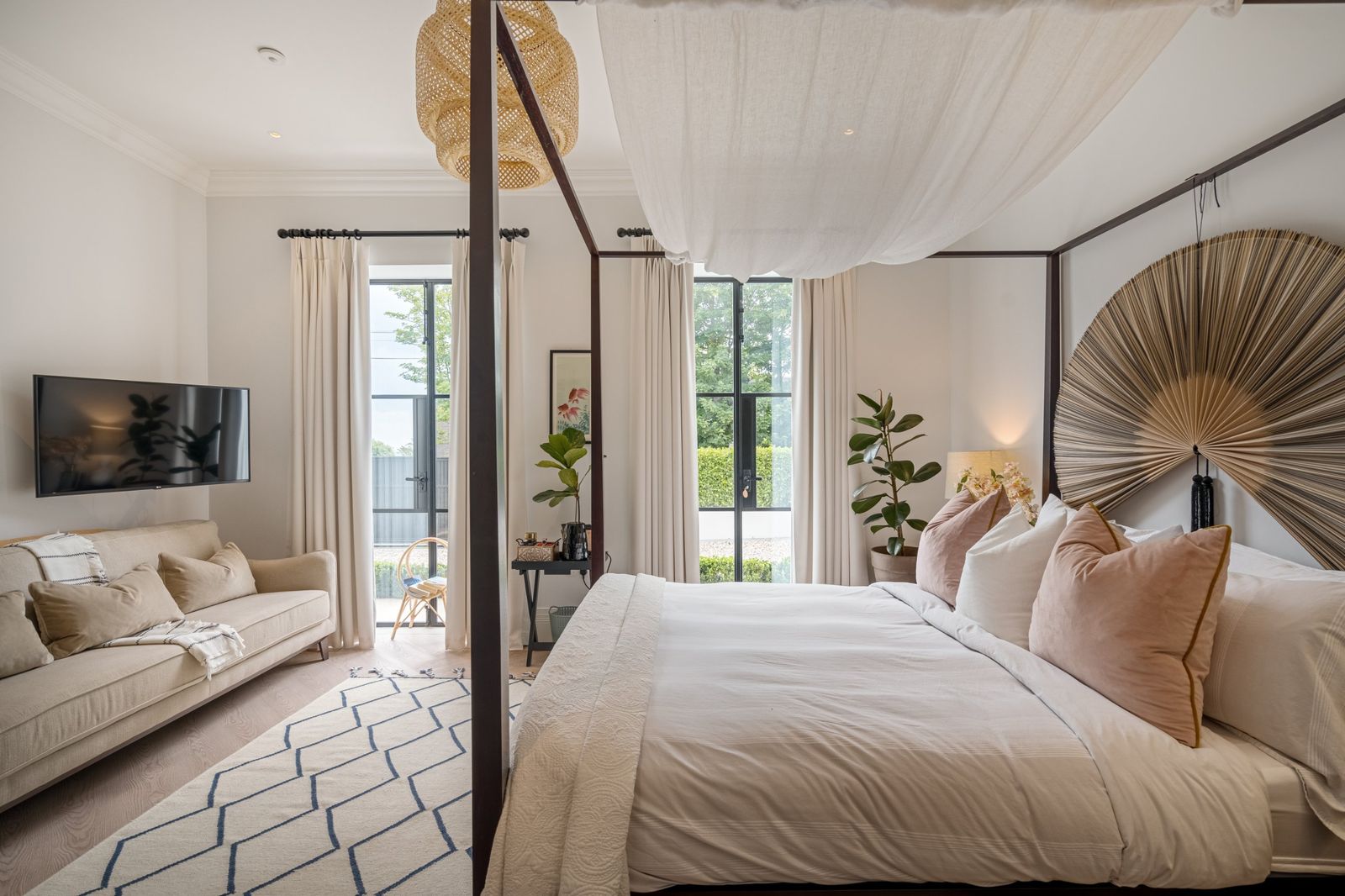 The bedroom with a four-poster bed and sofa by the garden doors