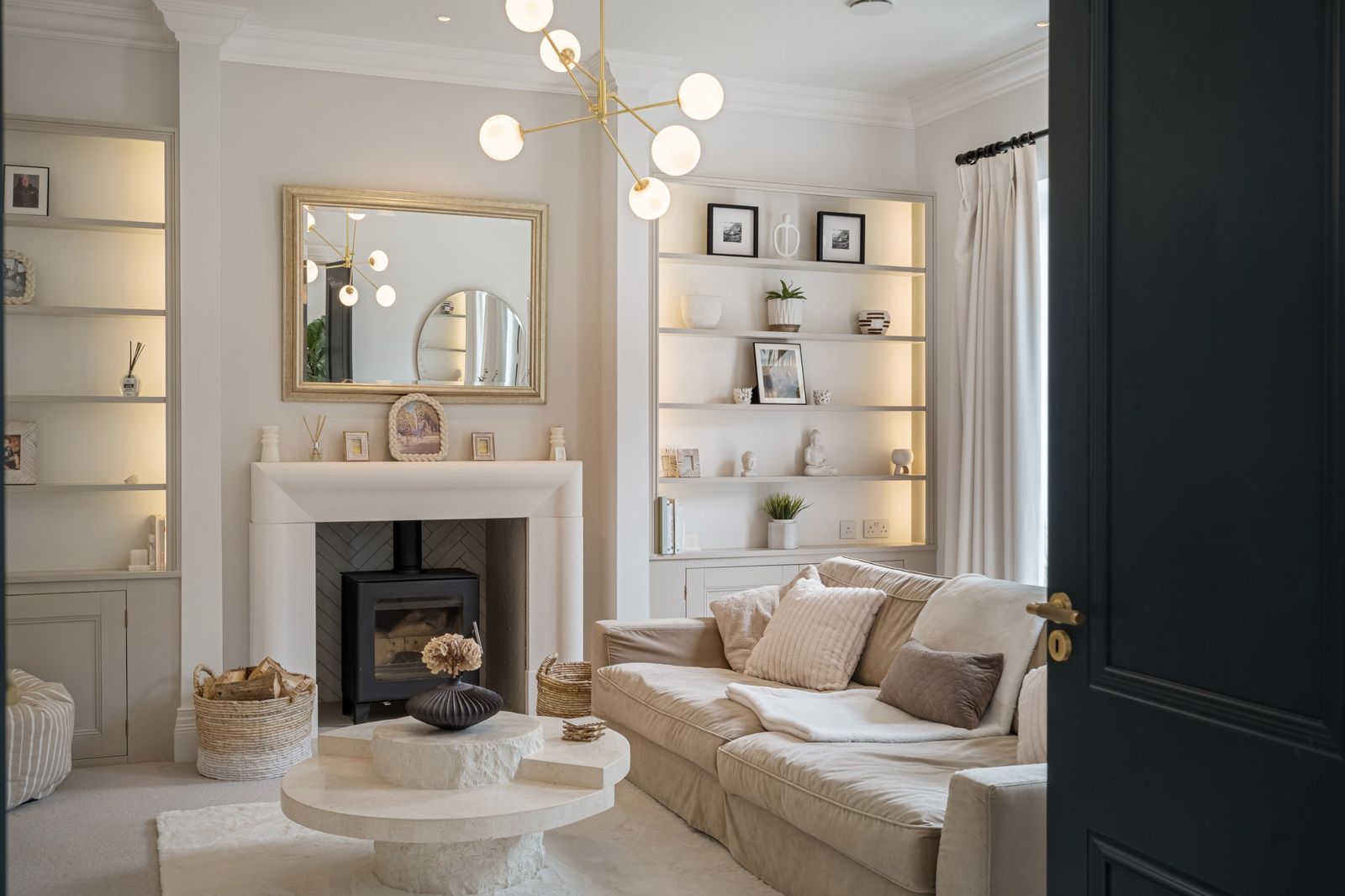 The sitting room with a stone fireplace and lit shelves