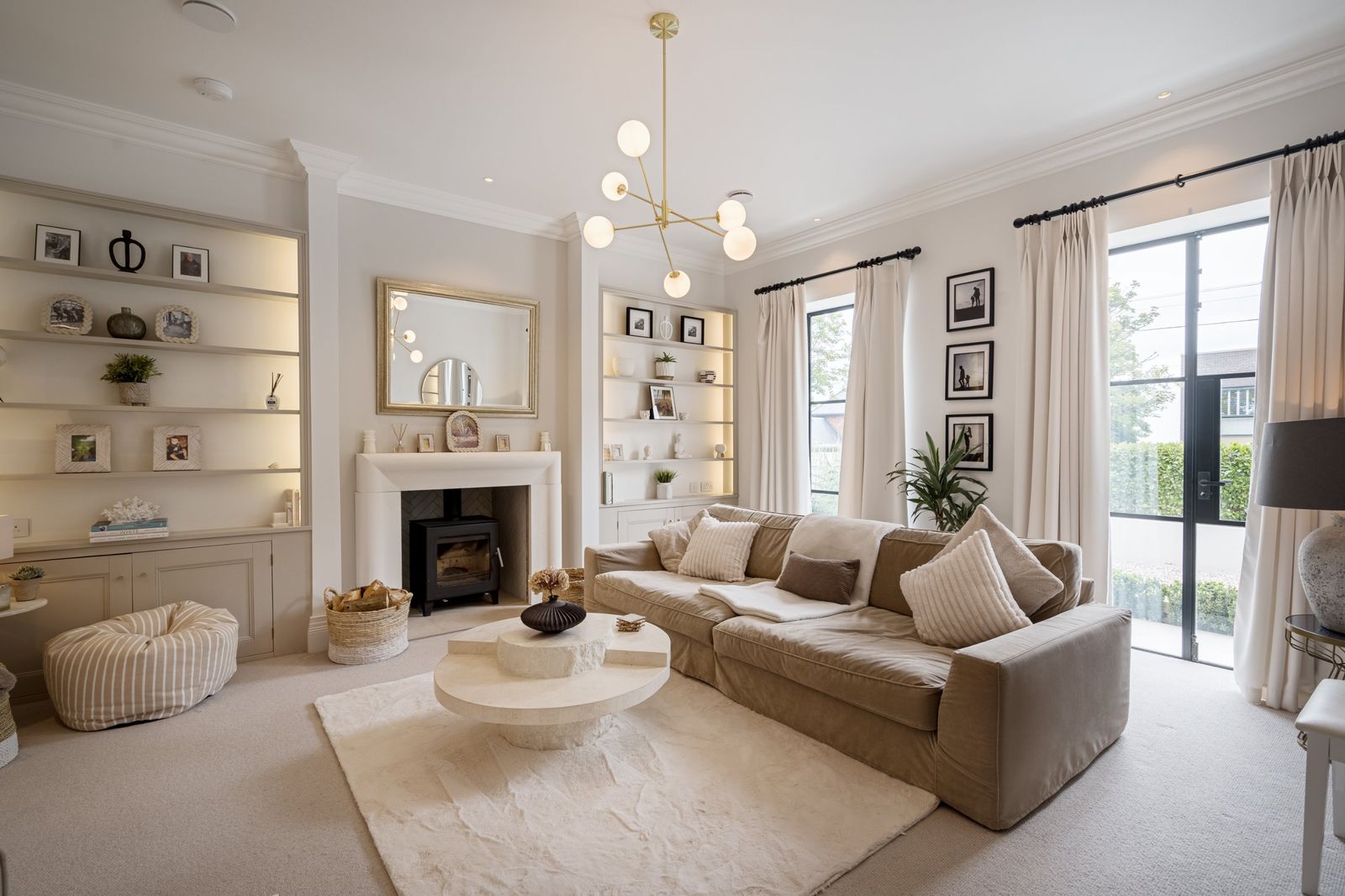 The sitting room with a wood burner, lit shelves and garden doors