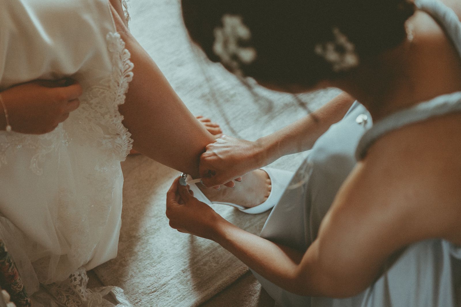 A bridesmaid fastening the bride's shoe